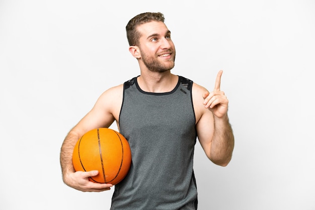 Jovem bonito jogando basquete sobre fundo branco isolado apontando para cima uma ótima idéia