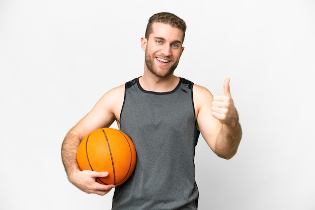 Jovem bonito jogando basquete sobre fundo branco isolado com polegares para cima porque algo de bom aconteceu