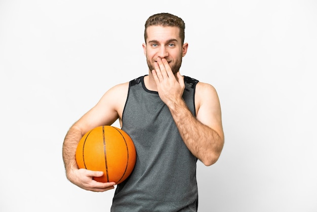 Jovem bonito jogando basquete sobre fundo branco isolado feliz e sorridente cobrindo a boca com a mão