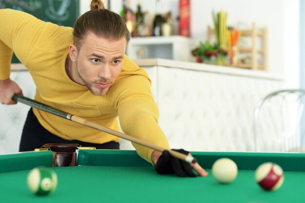 Jovem bonito jogando bilhar no clube de bilhar