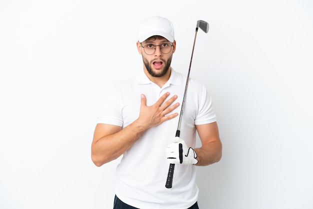 Jovem bonito jogando golfe isolado no fundo branco surpreso e chocado ao olhar para a direita