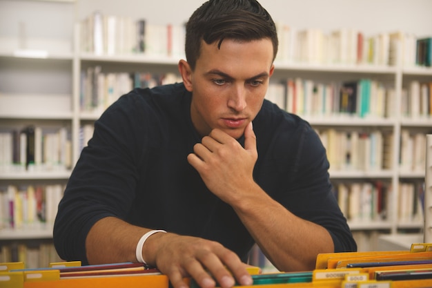 Jovem bonito lendo na biblioteca