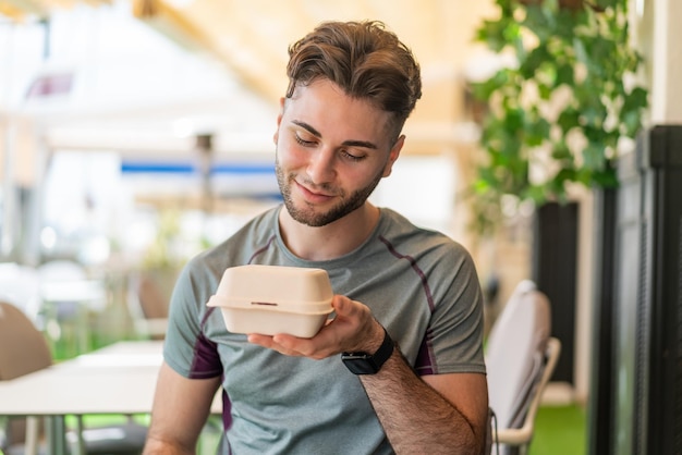 Jovem bonito levando uma caixa de comida para viagem