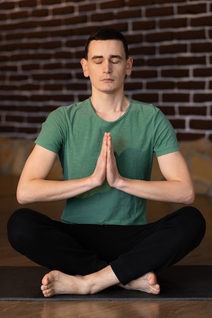 Jovem bonito meditando na sala de estar