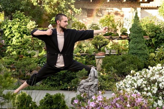 Jovem bonito meditando no jardim bonsai