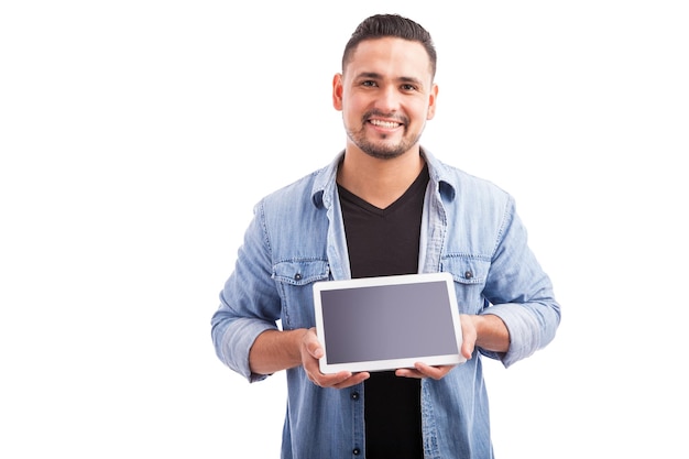 Jovem bonito mostrando a tela de um computador tablet e sorrindo