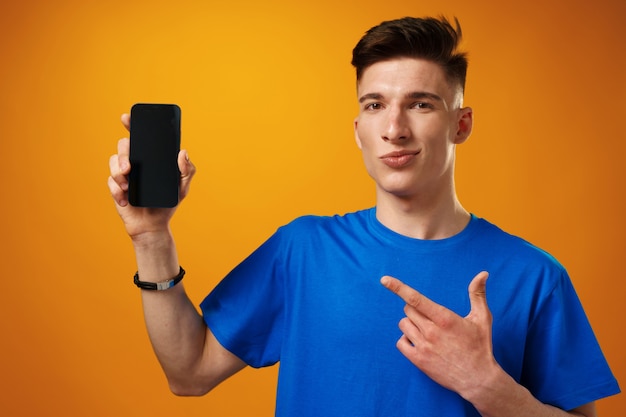 Jovem bonito mostrando tela preta de smartphone