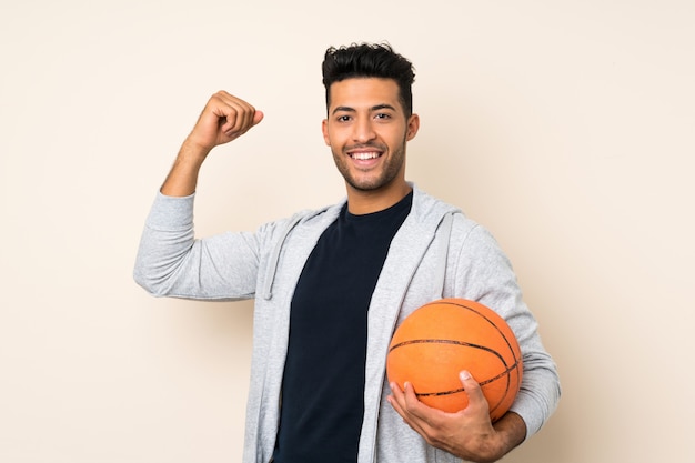 Jovem bonito muro isolado com bola de basquete