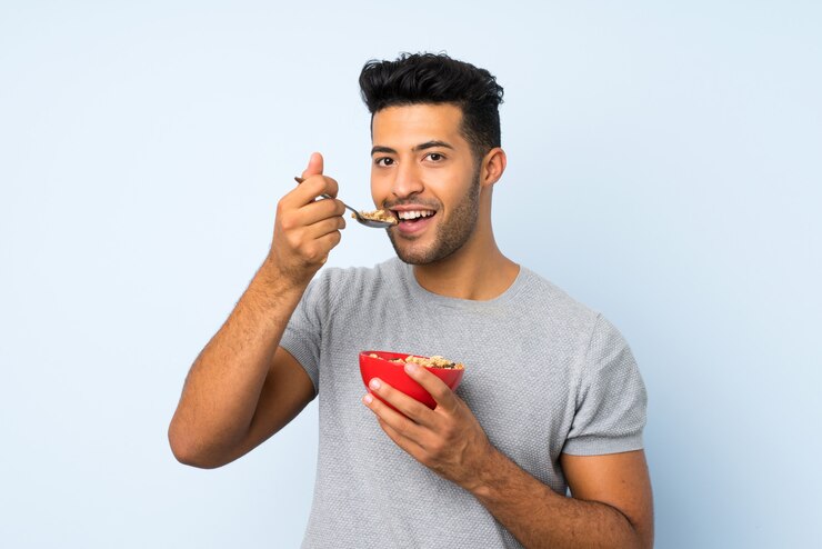 Foto jovem bonito muro isolado segurando uma tigela de cereais