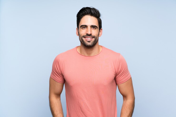 Foto jovem bonito na camisa rosa sobre parede azul isolada rindo