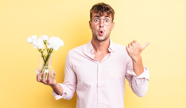 Jovem bonito olhando atônito na descrença. conceito de flores