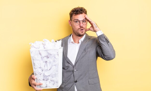 Jovem bonito olhando feliz, surpreso e surpreso conceito de lixo de bolas de papel