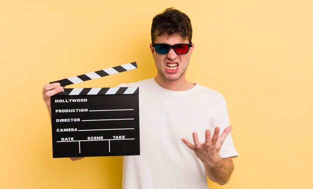 Jovem bonito olhando o conceito de badalo de cinema irritado e frustrado