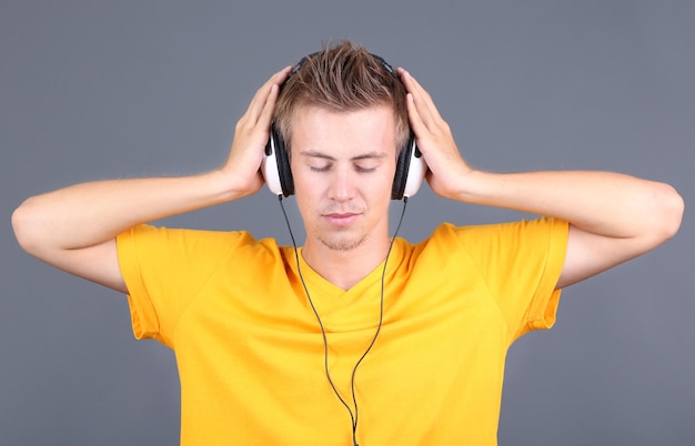 Jovem bonito ouvindo música em fundo cinza