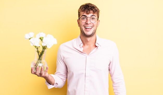 Jovem bonito parecendo feliz e agradavelmente surpreso. conceito de flores