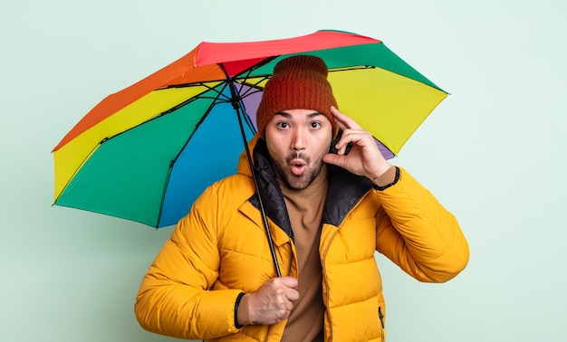 Jovem bonito parecendo feliz, espantado e surpreso. conceito de chuva e guarda-chuva