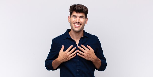 Jovem bonito parecendo feliz, surpreso, orgulhoso e animado, apontando para si mesmo