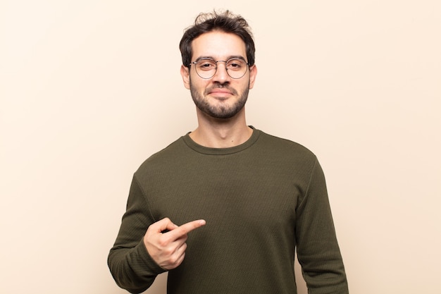 Jovem bonito parecendo orgulhoso, confiante e feliz, sorrindo e apontando para si mesmo ou fazendo o primeiro sinal