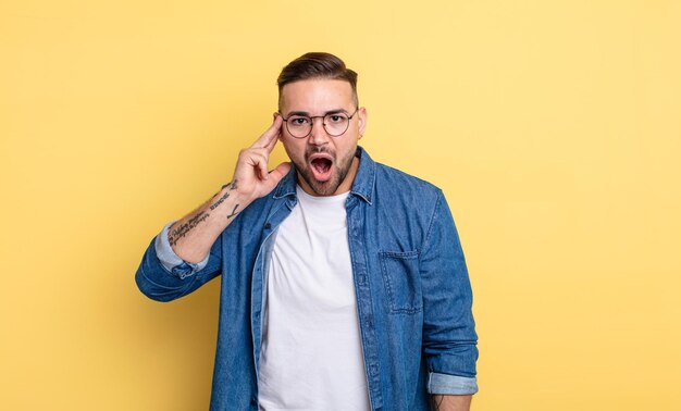 Jovem bonito parecendo surpreso, boquiaberto, chocado, percebendo um novo pensamento, ideia ou conceito