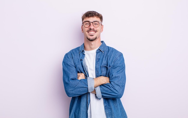 Jovem bonito, parecendo um empreendedor feliz, orgulhoso e satisfeito, sorrindo com os braços cruzados