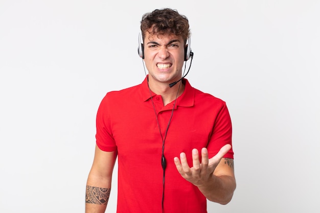 Jovem bonito parecendo zangado, irritado e frustrado. conceito de telemarketing