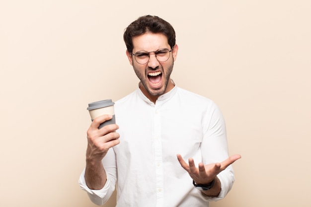 Jovem bonito parecendo zangado, irritado e frustrado gritando wtf ou o que há de errado com você