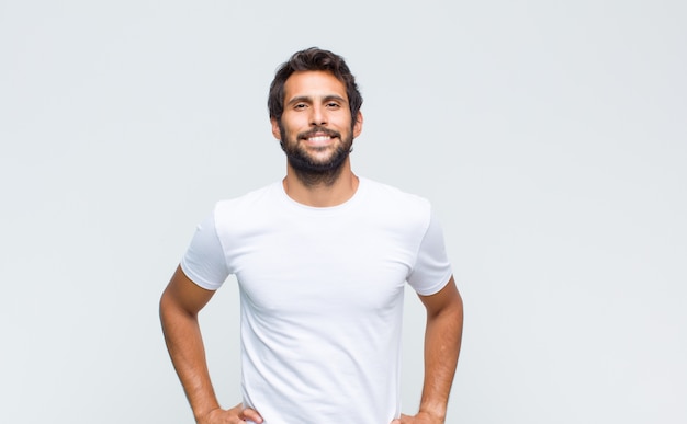 Foto jovem bonito posando e olhando para a câmera contra uma parede branca