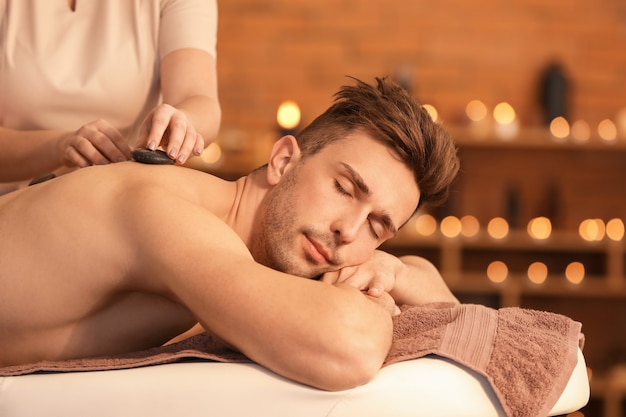 Jovem bonito recebendo massagem em salão de spa