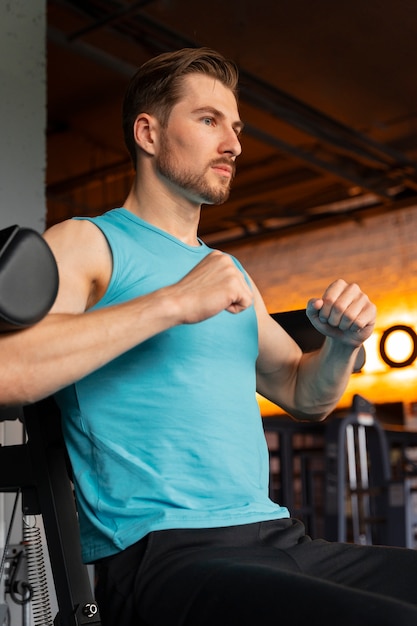 Foto jovem bonito se exercitando na academia de musculação