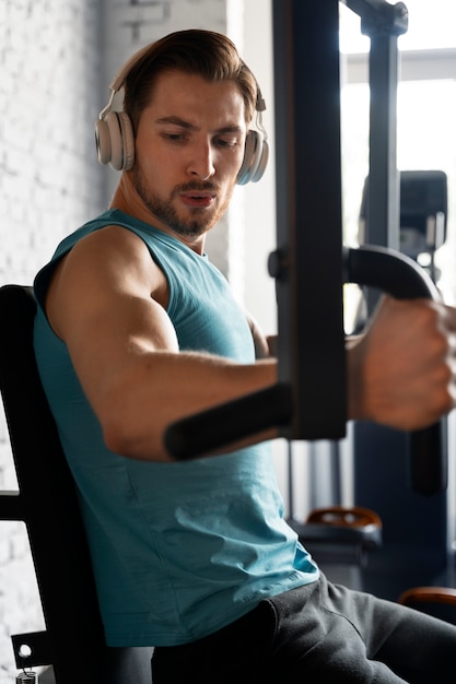 Foto jovem bonito se exercitando na academia de musculação