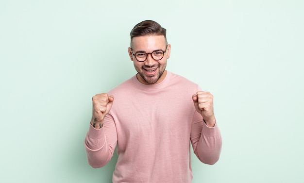 Jovem bonito se sentindo chocado, animado e feliz, rindo e comemorando o sucesso, dizendo uau!