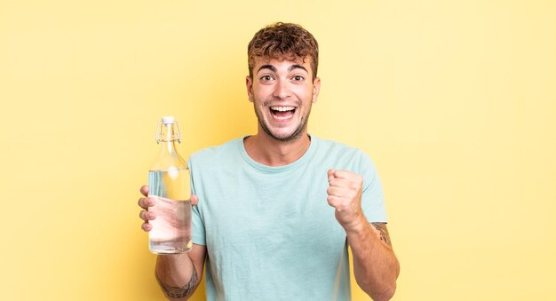 Jovem bonito se sentindo chocado rindo e comemorando o conceito de água de sucesso