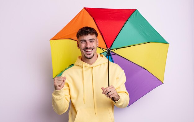 Jovem bonito se sentindo chocado, rindo e comemorando o sucesso. conceito de guarda-chuva