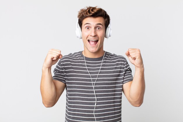 Jovem bonito se sentindo chocado, rindo e comemorando o sucesso. ouvir conceito de música