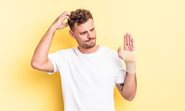 Jovem bonito se sentindo confuso e confuso, coçando a cabeça. conceito de bandagem de mão