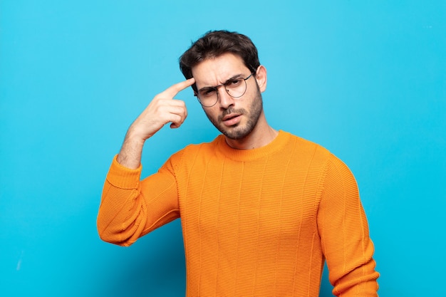 jovem bonito se sentindo confuso e perplexo, mostrando que você está louco, louco ou fora de si