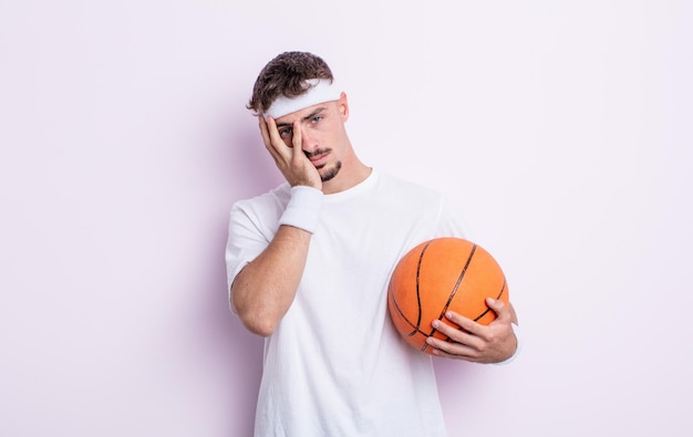 Jovem bonito se sentindo entediado, frustrado e com sono depois de um cansativo. conceito de basquete