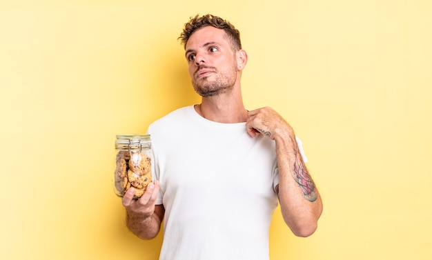 Jovem bonito se sentindo estressado, ansioso, cansado e frustrado conceito de garrafa de biscoitos