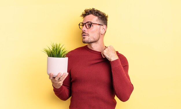 Jovem bonito se sentindo estressado, ansioso, cansado e frustrado. conceito de planta decorativa