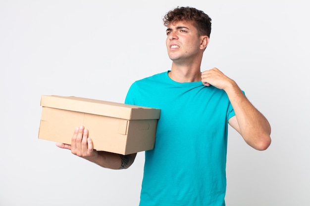 Jovem bonito se sentindo estressado, ansioso, cansado e frustrado e segurando uma caixa de papelão