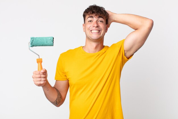 Jovem bonito se sentindo estressado, ansioso ou com medo, com as mãos na cabeça. conceito de pintura de casa