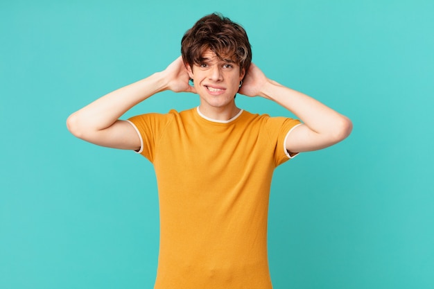 Jovem bonito se sentindo estressado, ansioso ou com medo, com as mãos na cabeça