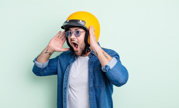 Jovem bonito se sentindo feliz, animado e surpreso. conceito de capacete de motocicleta