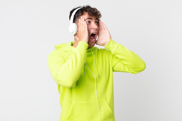 Jovem bonito se sentindo feliz, animado e surpreso e fones de ouvido