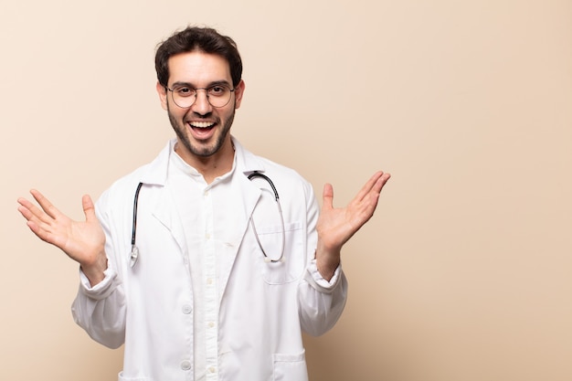 Jovem bonito se sentindo feliz, animado, surpreso ou chocado, sorrindo e surpreso com algo inacreditável