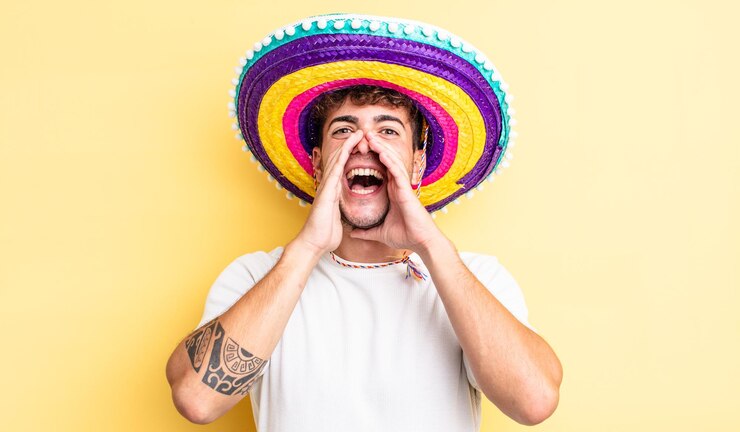 Foto jovem bonito se sentindo feliz dando um grande grito com as mãos ao lado do conceito de chapéu mexicano de boca