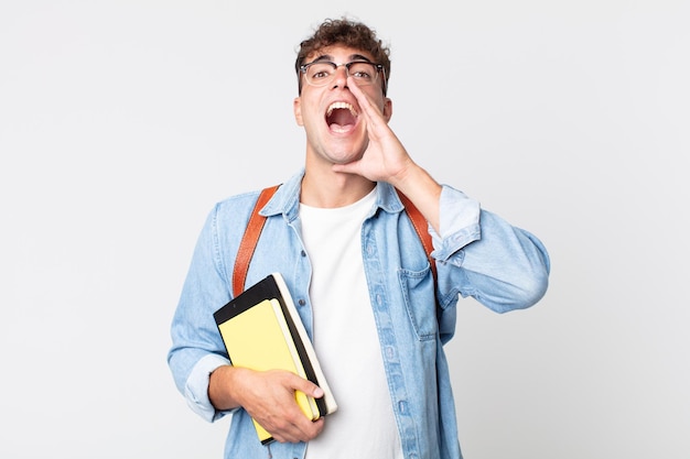 Jovem bonito se sentindo feliz, dando um grande grito com as mãos perto da boca. conceito de estudante universitário