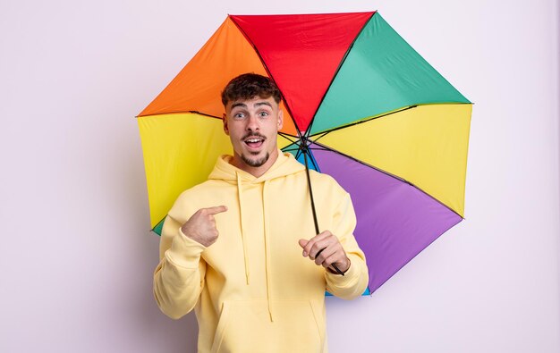 Jovem bonito se sentindo feliz e apontando para si mesmo com um animado. conceito de guarda-chuva