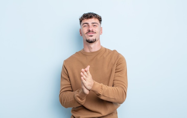 jovem bonito se sentindo feliz e bem sucedido, sorrindo e batendo palmas, dizendo parabéns com aplausos