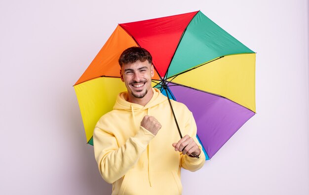 Jovem bonito se sentindo feliz e enfrentando um desafio ou comemorando. conceito de guarda-chuva